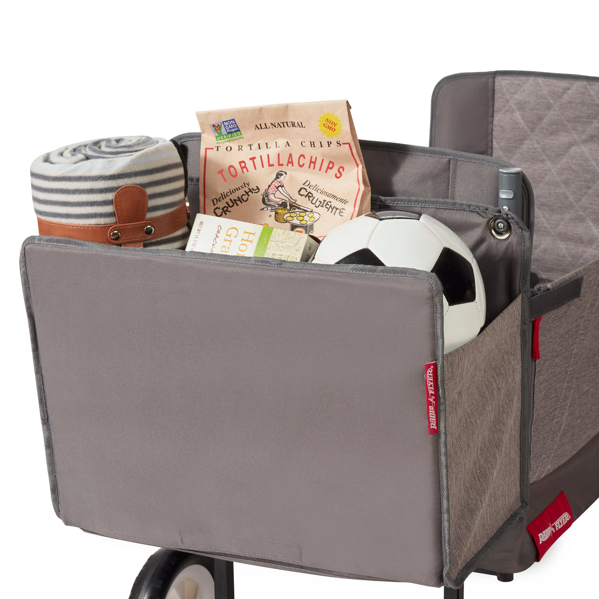 Gray rear storage bag on folding wagon filled with items including a bag of tortilla chips and a blanket.