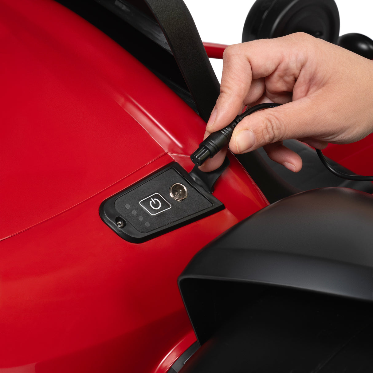 Hand plugging a charging cable into a red go kart charging port