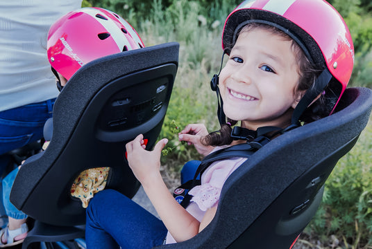 Child riding a Thule Yepp Seat, smiling.