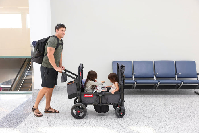 dad pushing two kids in a stroller wagon in airport