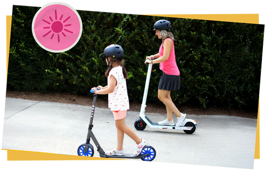 A child and a mom riding scooters on a sidewalk. 