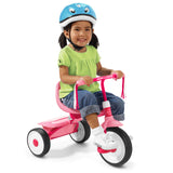 Child riding a pink tricycle with a blue helmet on a white background