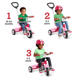 Three children wearing helmets are shown riding a pink three-wheel tricycle at three age stages: 18-24 months, 2-3 years, and 3-5 years. The tricycle has a pink frame and black wheels with white accents.