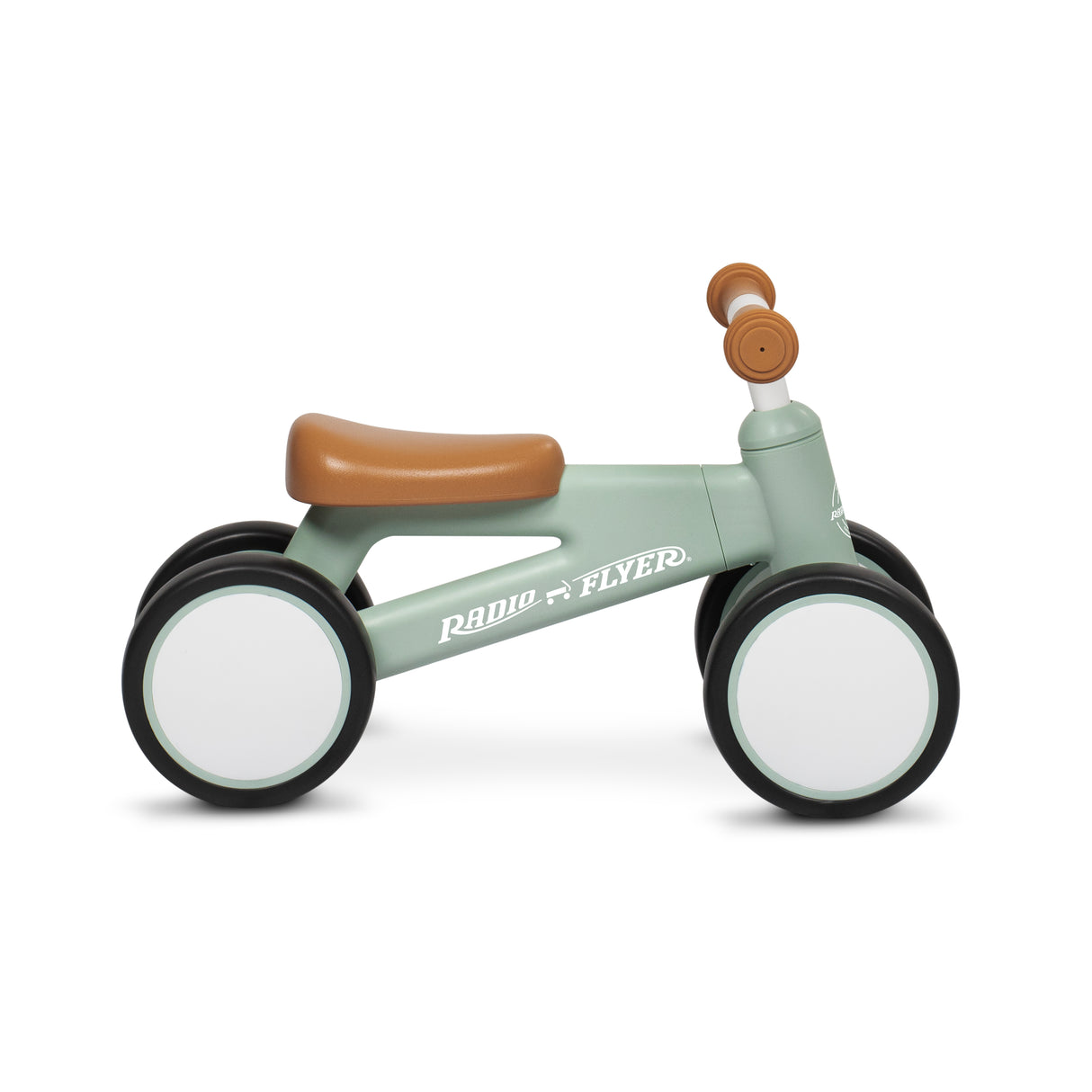 A Radio Flyer balance bike with a sage green frame, brown seat and handle grips, and white wheels, shown from a side profile on a white background.