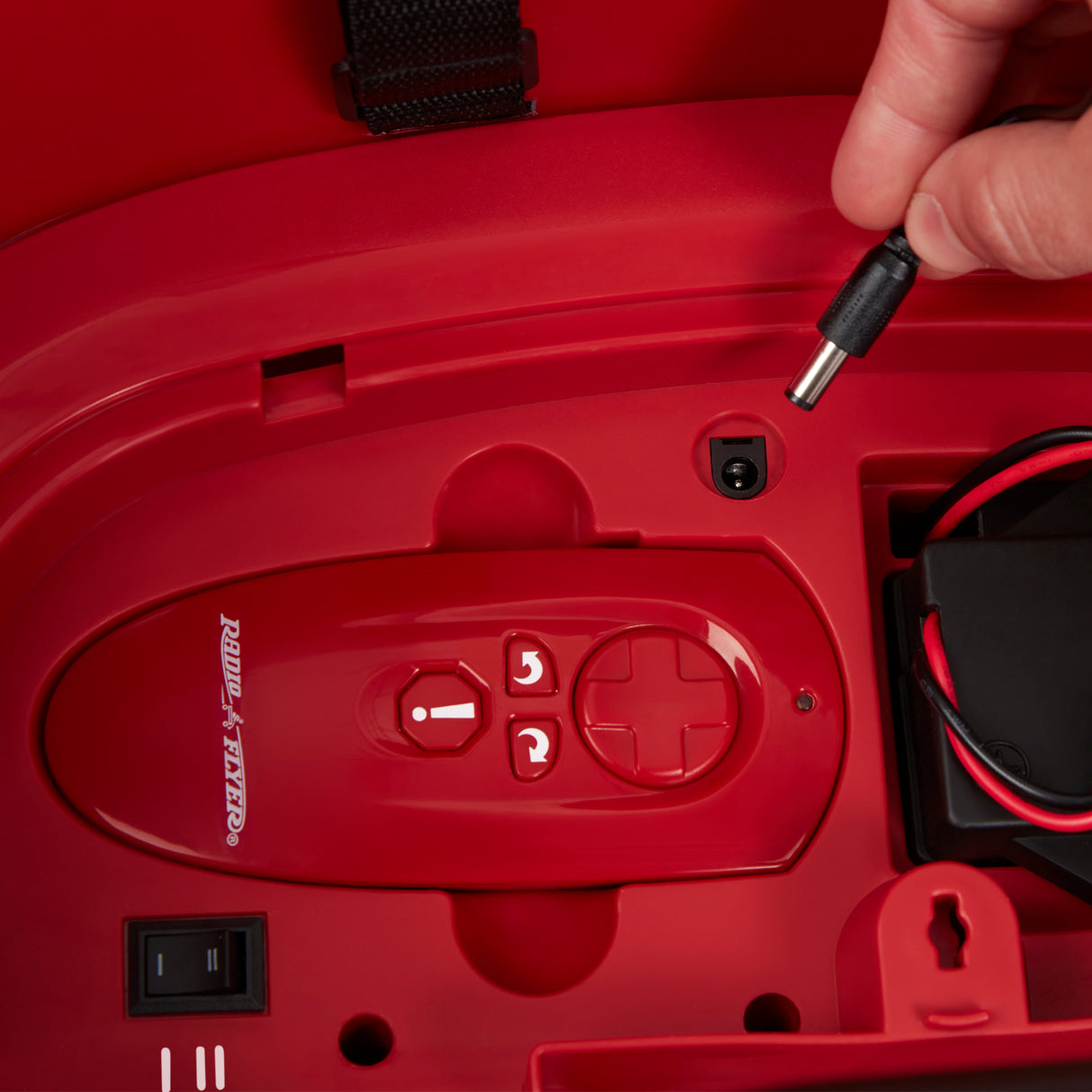 Close-up of the charging port beneath the seat with the charging cable positioned for easy battery charging