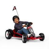 Child driving a red go kart with a helmet on a white background