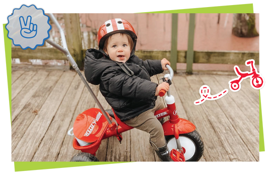 Child riding a red toy bike with safety helmet on a wooden deck