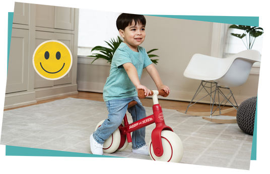 Child riding a balance bike in a room with a smiley face icon.
