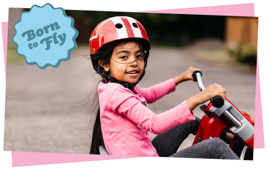 Child riding a chopper trike with a 'born to fly' sticker overlayed.