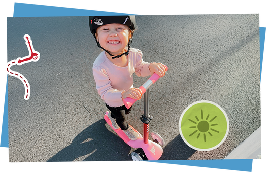 Child riding a pink scooter with a helmet.