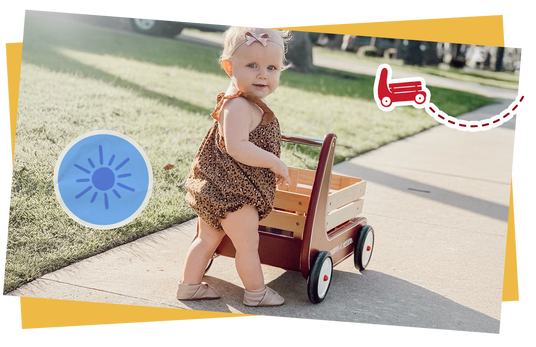 Child pushing a Radio Flyer walker wagon on the sidewalk.
